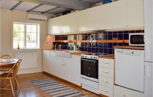 a kitchen with white appliances and a table and a window at Lovely Home In Lammhult With Wifi in Lammhult