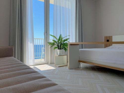 a bedroom with a bed and a large window at Hotel Corallo in Imperia