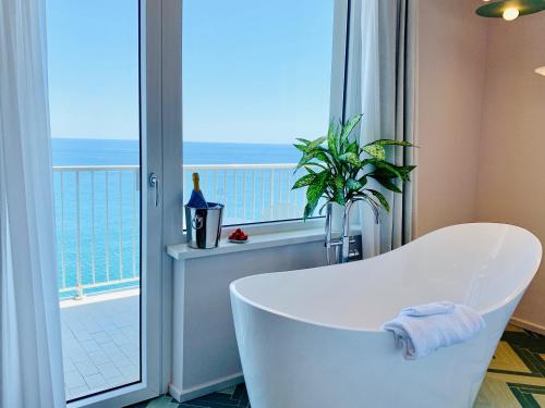 a white bath tub sitting in front of a window at Hotel Corallo in Imperia