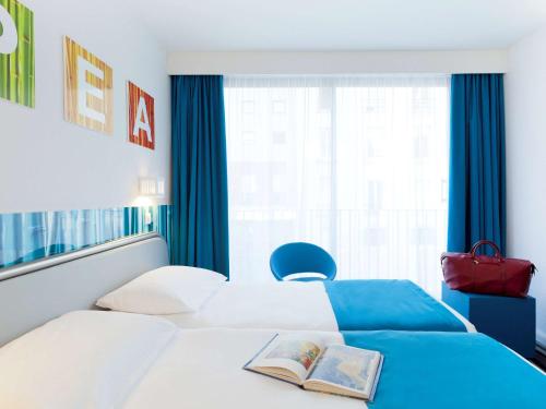 a hotel room with a bed with a book on it at ibis Styles Paris Porte d'Orléans in Montrouge