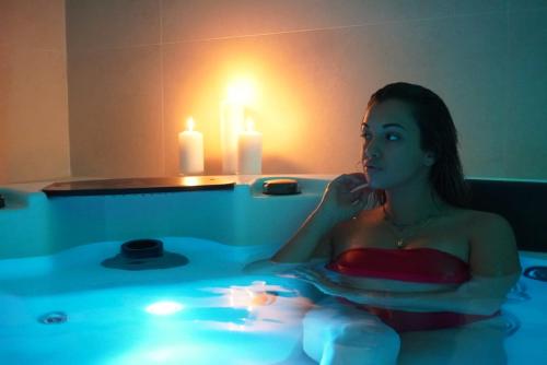 Una donna seduta in una vasca da bagno con una candela di Hotel Galli - Wellness & Spa a Fetovaia