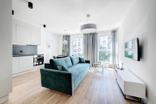 a living room with a blue couch and a kitchen at Old Town Apartments - Św. Barbary street by Renters in Gdańsk