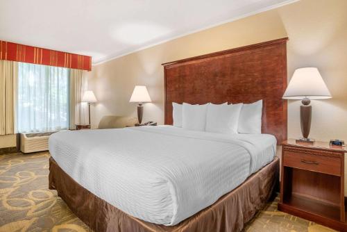 a large bed in a hotel room with two lamps at Clarion Inn Conference Center in Gonzales