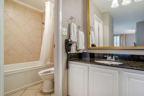 a bathroom with a sink and a toilet and a mirror at Clarion Inn Conference Center in Gonzales