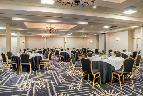 a banquet room with tables and chairs and a chandelier at Clarion Inn Conference Center in Gonzales