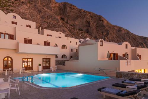 a hotel with a swimming pool in front of a mountain at Epavlis Hotel & Spa in Kamari