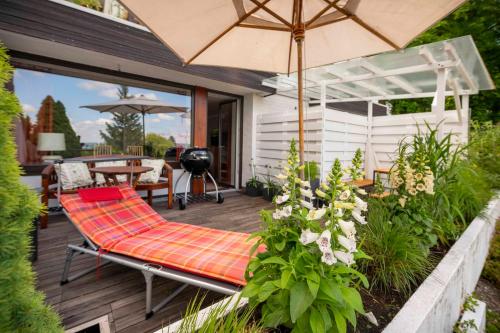 a bench on a deck with an umbrella at Petras Ammerseeblick in Herrsching am Ammersee