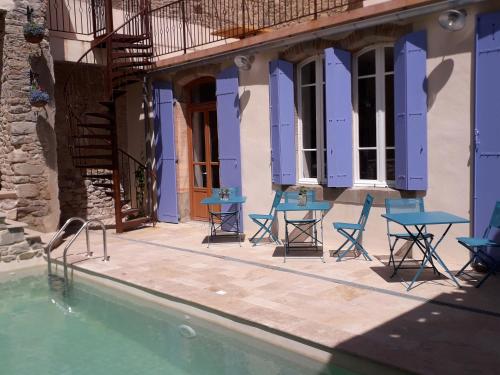 a house with blue tables and chairs next to a swimming pool at La Sentinelle in Siran
