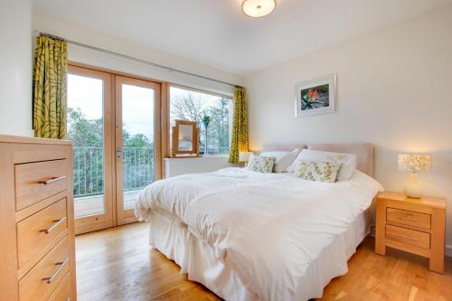 ein Schlafzimmer mit einem weißen Bett und einem großen Fenster in der Unterkunft The Old Stables Aberdyfi apartment 6 in Aberdyfi