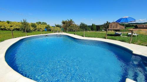 a large blue swimming pool with an umbrella at Agriturismo Il Tondino in Tabiano