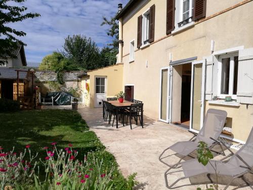 a patio with a table and chairs next to a building at Celine'Home in Saint-Germain-sur-Morin