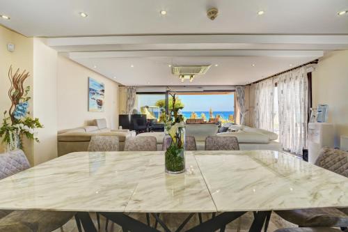 a dining room with a table and a living room at Seafront Protaras Villas in Protaras