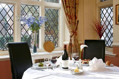 a table with a bottle of wine and glasses at voco Letchworth Hall by IHG in Letchworth