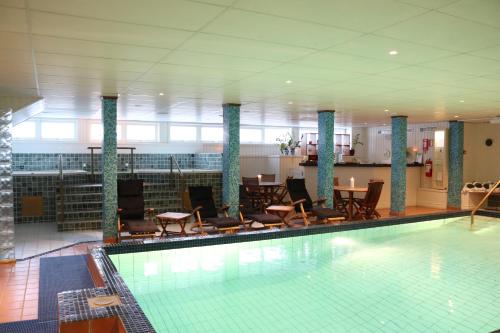 - une piscine avec des chaises et des tables dans un bâtiment dans l'établissement Mora Hotell & Spa, à Mora