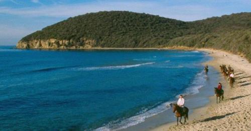 a group of people riding horses on the beach at La grotta nel borgo in Roccastrada