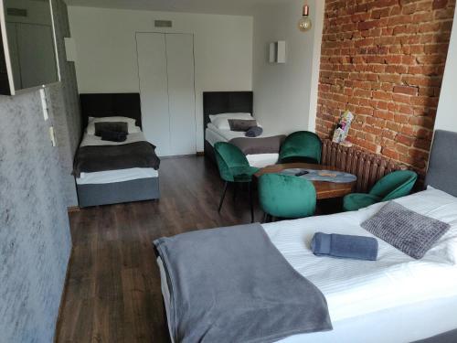 een kamer met 2 bedden en een bakstenen muur bij Apartament Studio 11 Starówka Konin in Konin