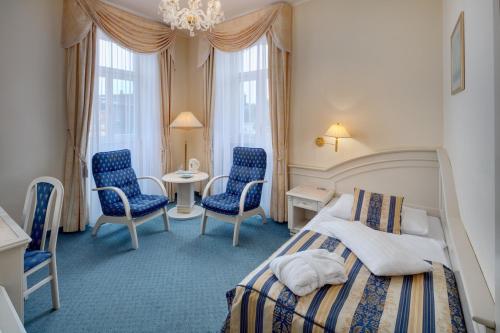 - une chambre avec un lit, deux chaises et une table dans l'établissement Ensana Hotel Pacifik, à Mariánské Lázně