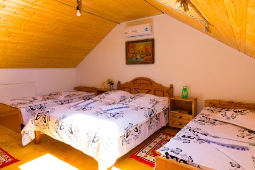 two beds in a bedroom with wooden ceilings at Casa de vacanta Marya in Baia de Fier