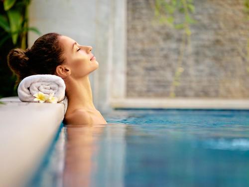 a woman laying on the edge of a swimming pool at Hotel De Maasparel Arcen - Venlo in Arcen