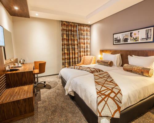 um quarto de hotel com duas camas e uma secretária em City Lodge Newtown, Johannesburg em Joanesburgo