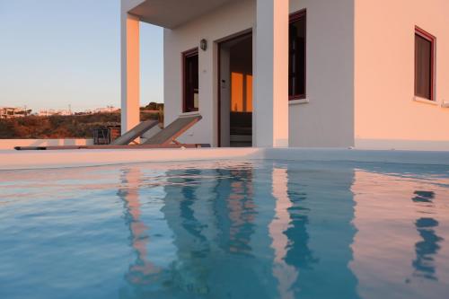 a villa with a swimming pool next to a house at Aplada Suites in Oia