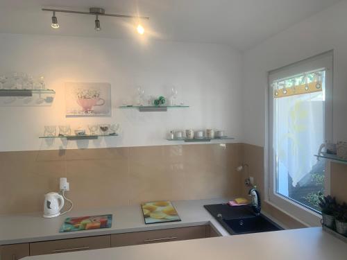 eine Küche mit einer Theke, einem Waschbecken und einem Fenster in der Unterkunft Apartamenty Kris in Mikołajki