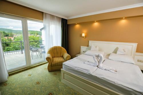 sypialnia z łóżkiem, krzesłem i oknem w obiekcie Calimbra Wellness Hotel Superior w Miskolc-Tapolca