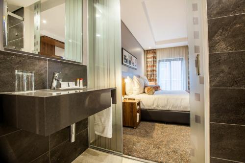 a bathroom with a sink and a bed in a room at City Lodge Newtown, Johannesburg in Johannesburg