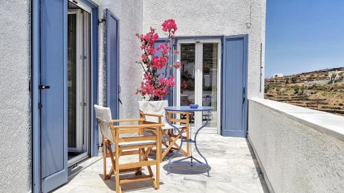 a balcony with chairs and a table and flowers at Tinoshomelidays Residences in Venardatos