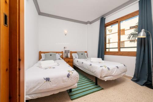 two beds in a room with a window at Apartamento Lortal in Alcudia