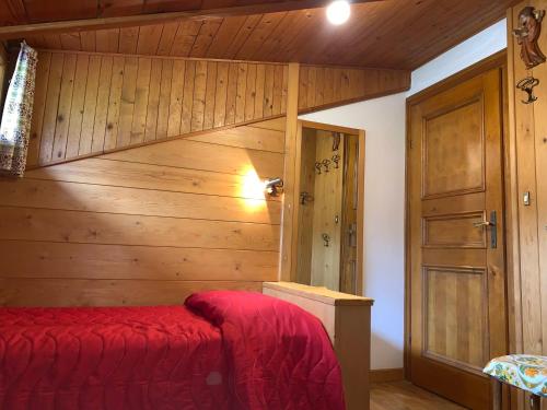una camera con letto rosso e parete in legno di Attico Vista Tofane a Cortina dʼAmpezzo