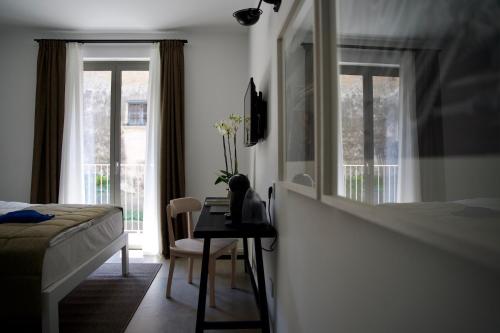 a bedroom with a bed and a desk and windows at Seta Hotel in Bellagio