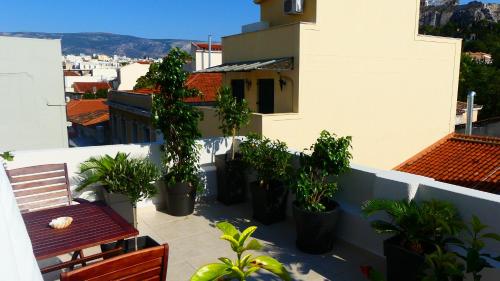 a balcony with potted plants and a bench on a building at Theasis Athens in Athens