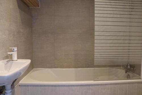 y baño con bañera y lavamanos. en Le Risle - Hôtel, en Montfort-sur-Risle