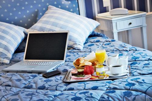 een dienblad met ontbijt op een bed met een laptop bij Golden Tulip Washington Opera in Parijs