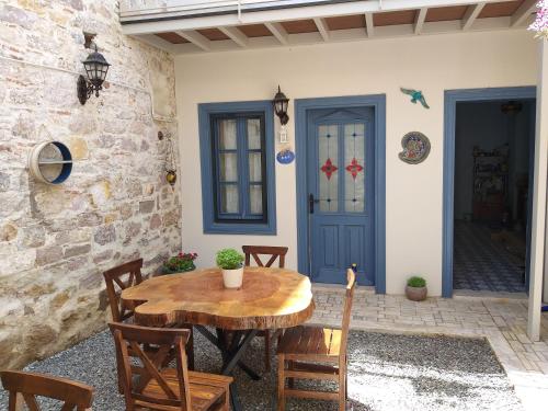 a patio with a wooden table and chairs and a blue door at Gizemli Konak in Ayvalık