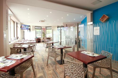 a restaurant with wooden tables and chairs and blue walls at Hôtel La Couronne in Marmande