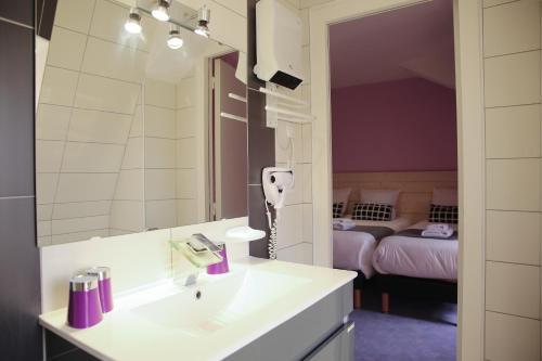 マルマンドにあるHôtel La Couronneの洗面台と鏡とベッドのあるバスルーム