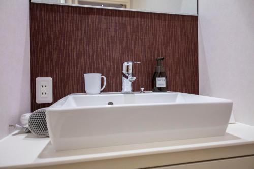 a white sink with a bottle of wine on a counter at GRAND BASE Okayama Ekimae in Okayama