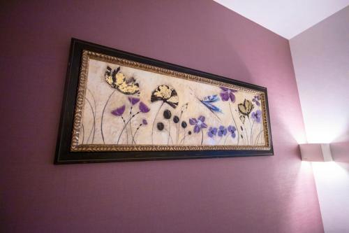 a picture of flowers hanging on a purple wall at GRAND BASE Okayama Ekimae in Okayama