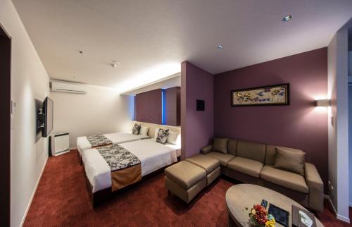a hotel room with a bed and a couch at GRAND BASE Okayama Ekimae in Okayama