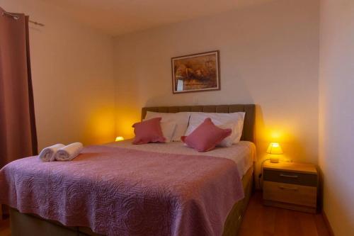 a bedroom with a bed with pink pillows and two lamps at Apartments Vladimir #3 in Makarska