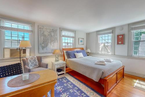 een slaapkamer met een bed, een stoel en ramen bij Maine Memories in Wiscasset