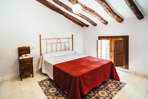 1 dormitorio con 1 cama grande con manta roja en La Casa del Boticario, en Alcalá del Júcar