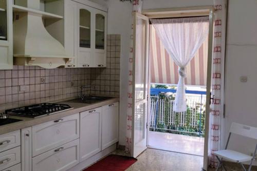 ガエータにあるLa casa di Ulisseの白いキャビネットと大きな窓のあるキッチン