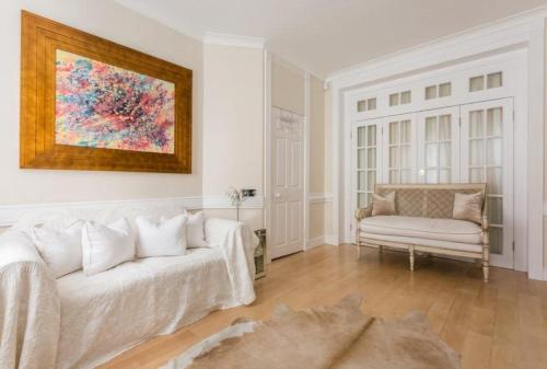 Una sala de estar con un sofá blanco y una silla. en Marylebone Luxury 3BR Flat Elegant Central Gem, en Londres