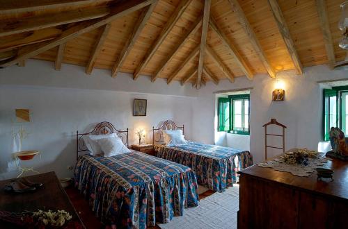 a bedroom with two beds in a room with wooden ceilings at Aldeia da Mata Pequena in Mafra