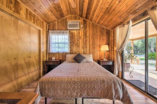 a bedroom with a bed in a room with wooden walls at Couples Cabin with Luxury Deck, 1 Mi to Canyon Lake! in Canyon Lake