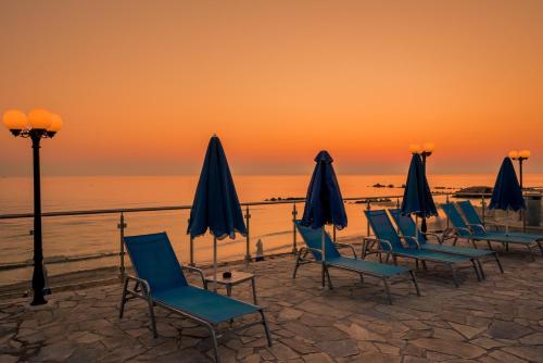 a group of chairs and umbrellas on the beach at sunset at Boletsos Beach in Argasi