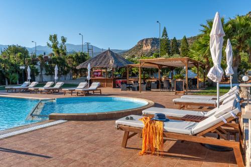 a resort pool with lounge chairs and a table at W Suites by Estia in Stalida